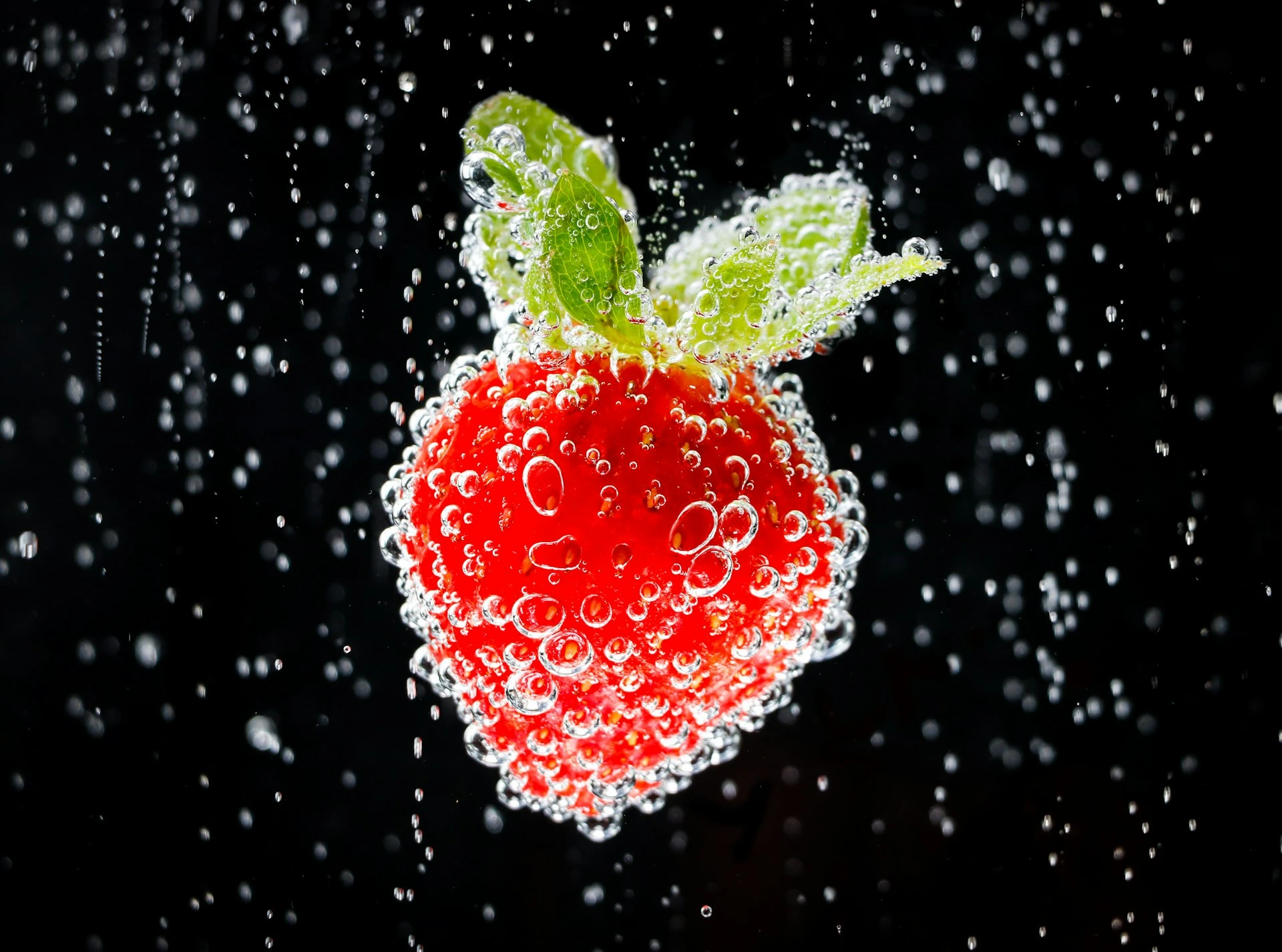 A strawberry submerged in fizzy water with bubbles.